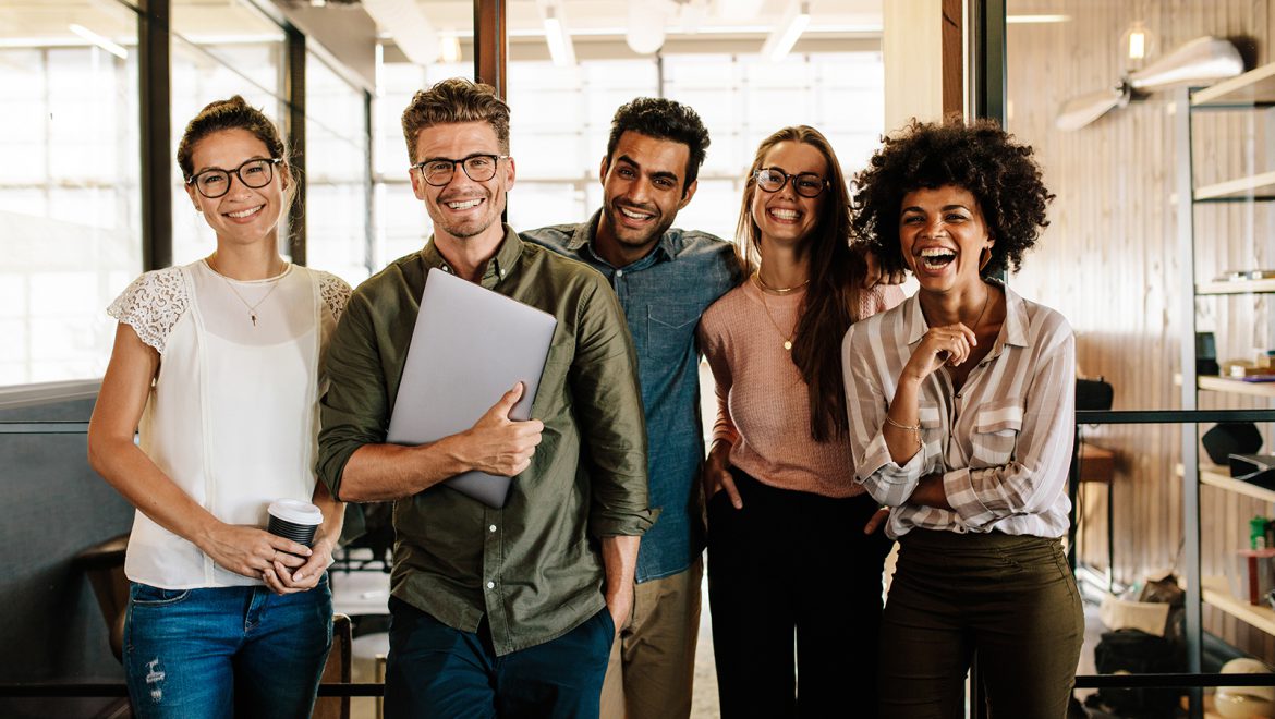 Five people laughing together in a bright studio